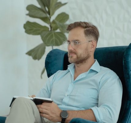 Male counselor in a modern office chair taking notes, promoting mental health awareness.